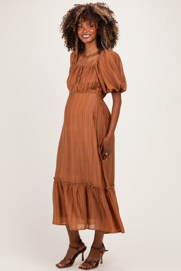 woman wearing a rust-colored maternity dress with puff sleeves and ruffle hem, showing her baby bump