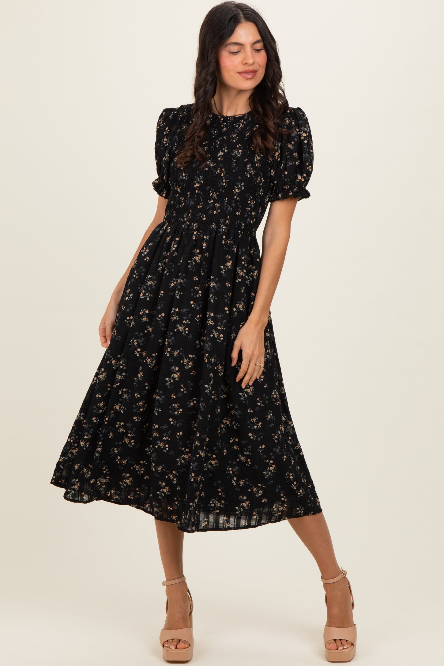woman wearing a black floral puff sleeve midi dress with a smocked bodice and a flowing skirt