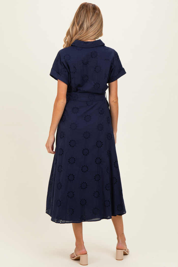 woman wearing a navy blue maternity wrap dress with floral embroidery and short sleeves, view from the back