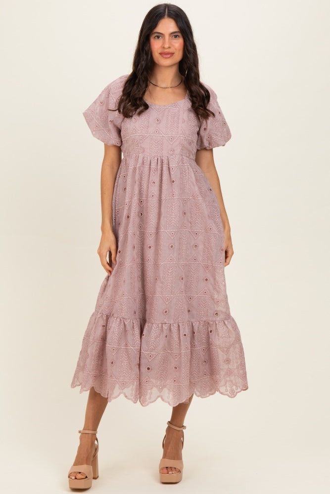 woman wearing a light mauve puff sleeve midi dress with a tiered ruffle hem and eyelet lace detailing