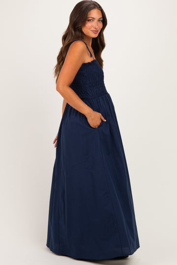 woman wearing a navy blue maternity maxi dress with a smocked bodice and side pockets