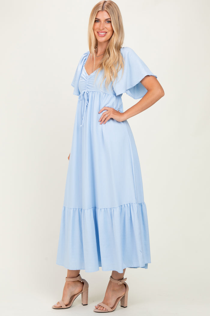 woman wearing a light blue maxi dress with flutter sleeves and a tie waist detail