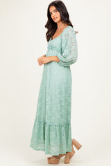 woman wearing a mint green lace maxi dress with puff sleeves and a flouncy hem, standing profile
