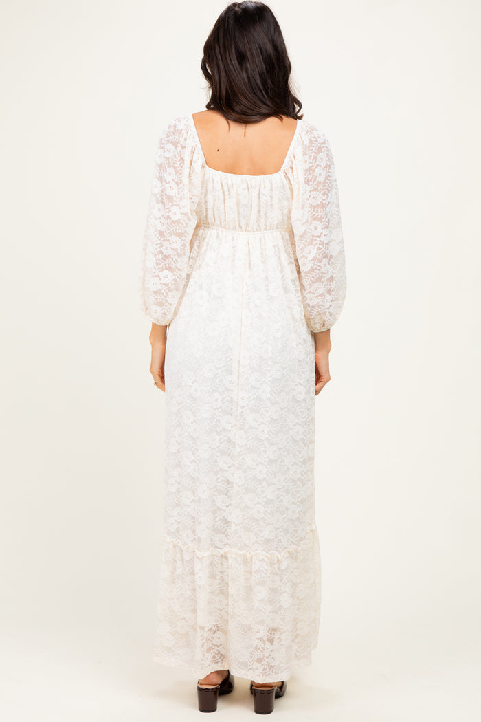 woman wearing a cream lace maxi dress with puff sleeves and a tiered hem, viewed from the back