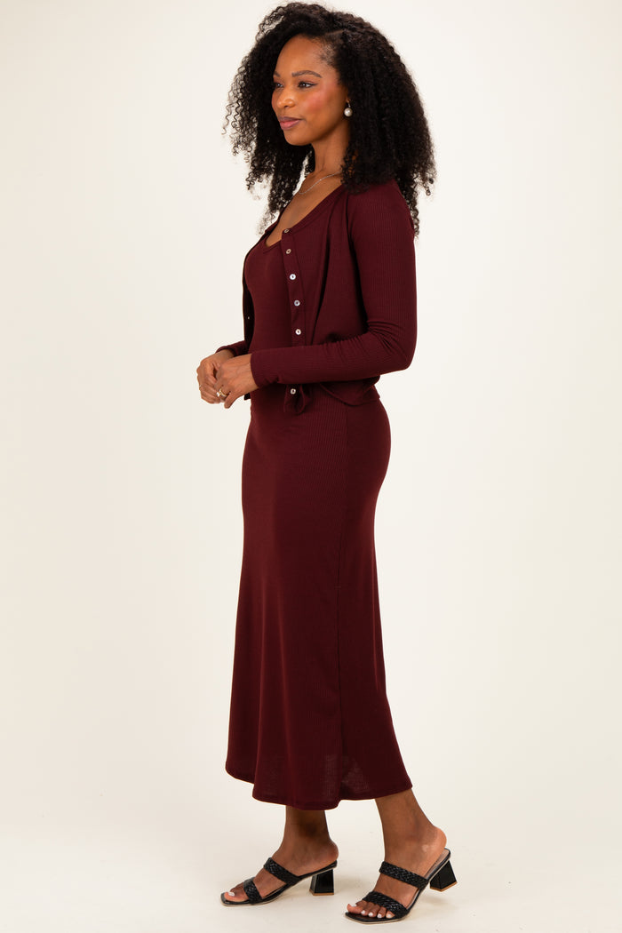 woman wearing a burgundy ribbed maxi dress with a matching button-up cardigan and black heeled sandals