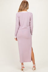 woman wearing a lavender long sleeve maternity dress with a side split, showing her back and hair down