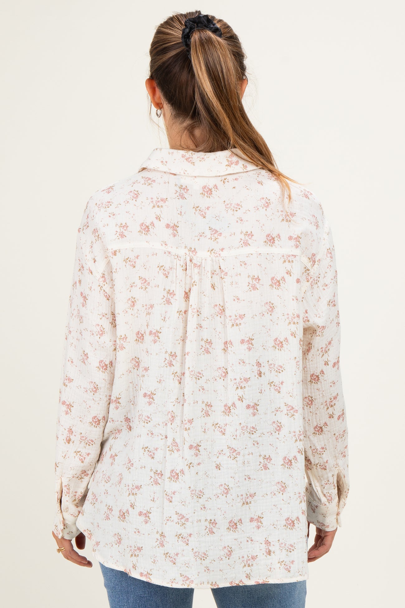 woman wearing a white floral maternity top with long sleeves, shown from the back