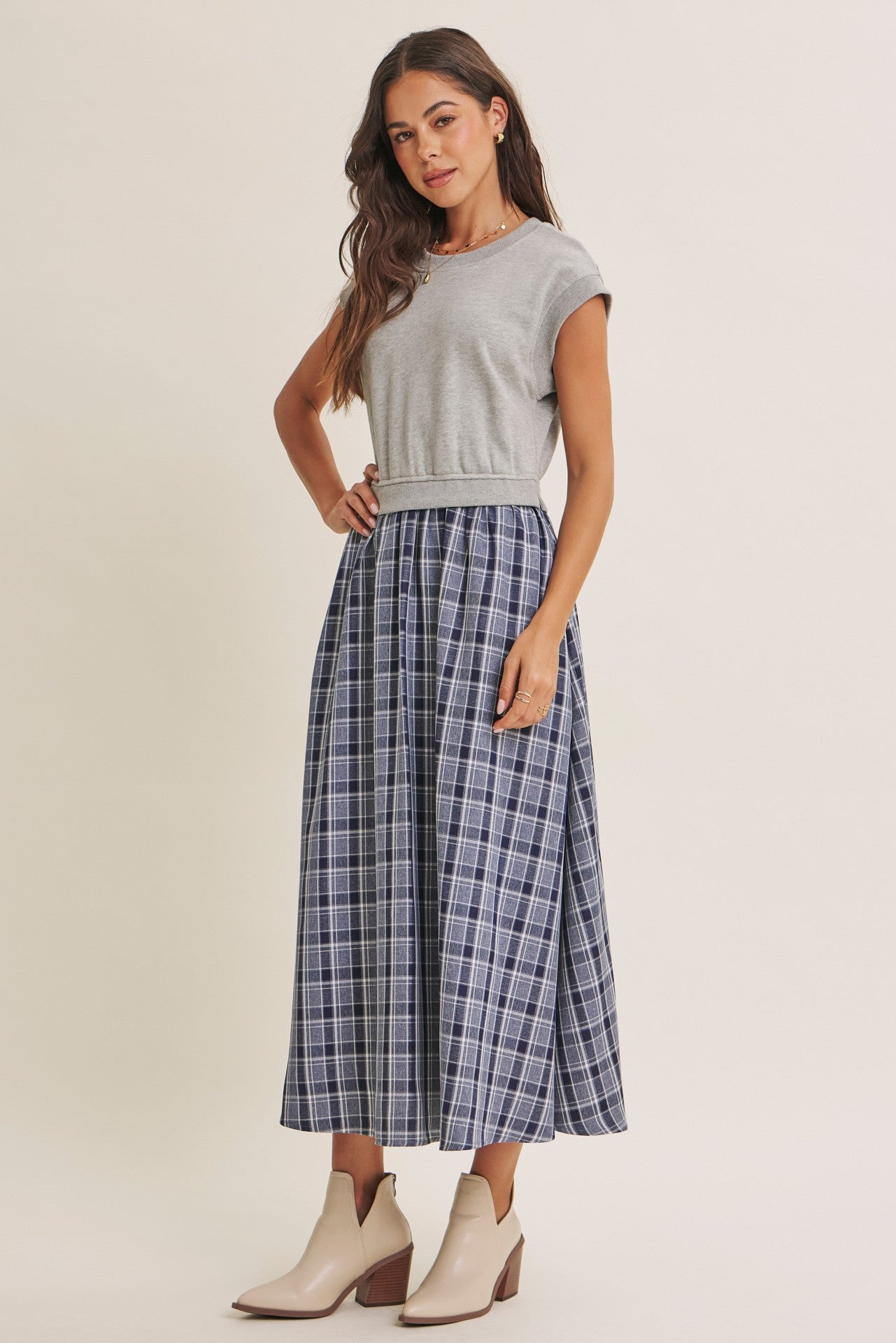 woman wearing a gray short sleeve top and a navy plaid maxi skirt with beige ankle boots