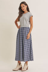 woman wearing a gray short sleeve top and a navy plaid maxi skirt with beige ankle boots