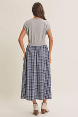 woman wearing a gray short sleeve top and a long navy plaid skirt from the back