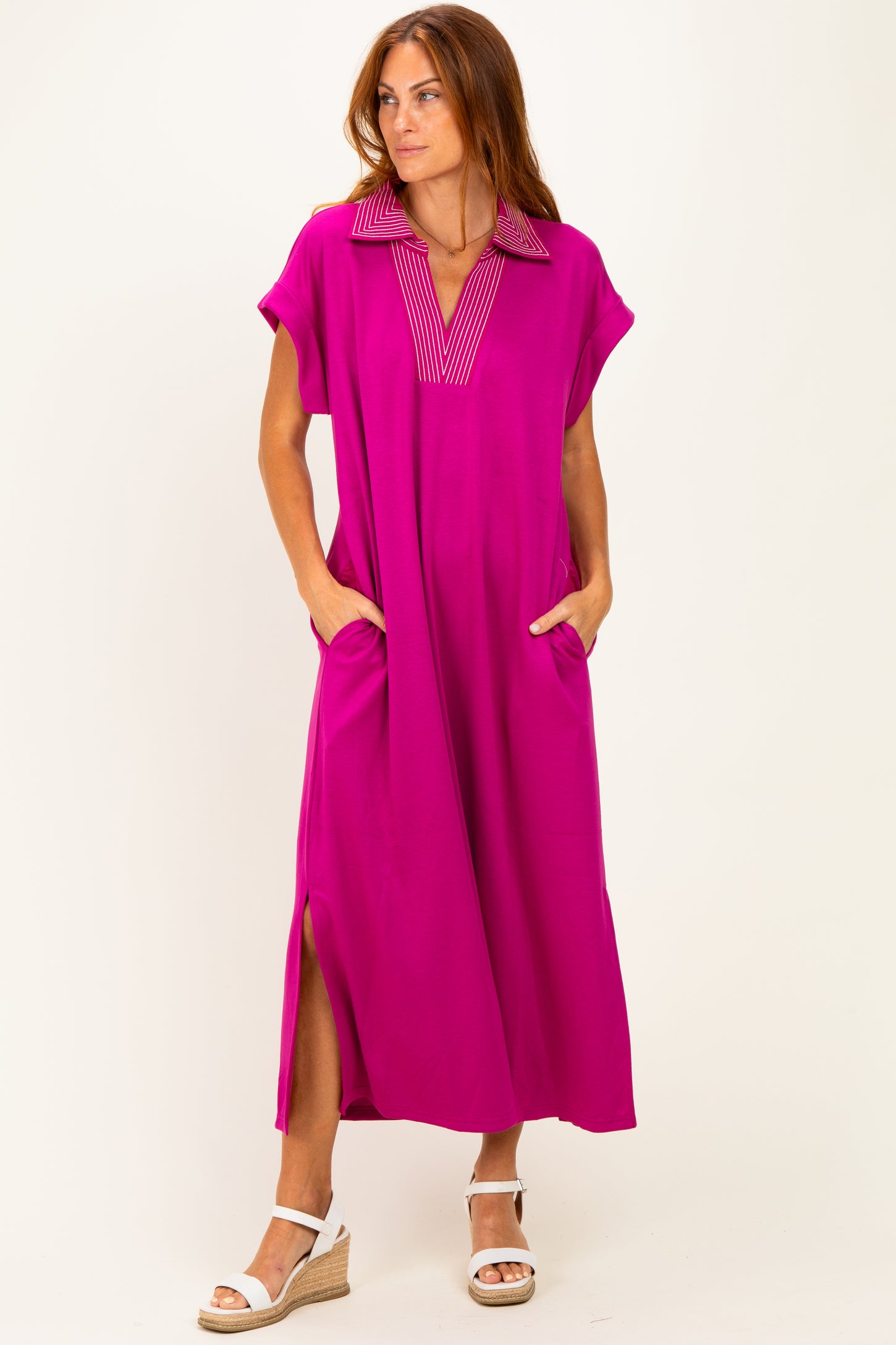 woman wearing a bright pink maxi dress with a collar and side pockets, standing against a white background