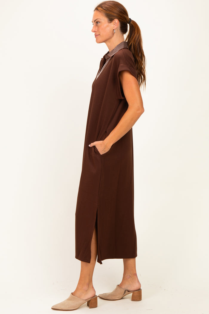woman wearing a brown maxi dress with short sleeves and side pockets, standing sideways with a relaxed fit