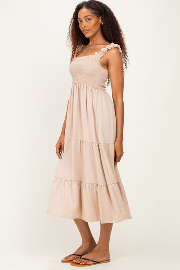 woman wearing a beige tiered maxi dress with ruffle straps and smocked bodice, standing sideways