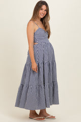woman wearing a navy and white gingham maternity dress with cut-out details and a tiered skirt, showcasing her baby bump