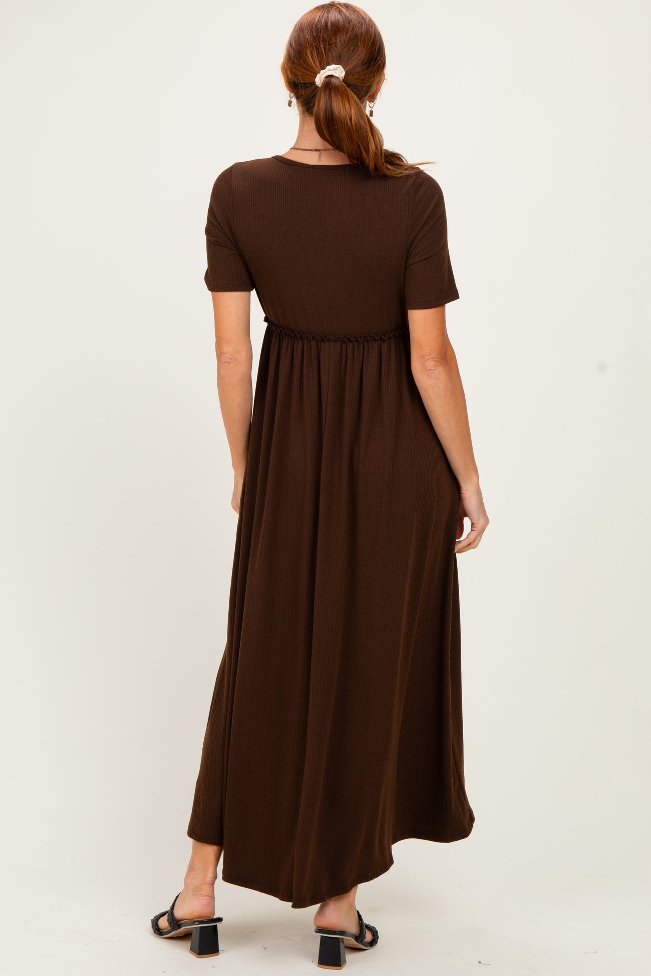woman wearing a brown short sleeve maxi dress with an elastic waist and flowing skirt, seen from the back