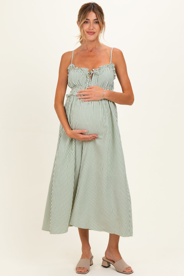 woman wearing a green and white striped maternity dress with tie-front detail and holding her baby bump
