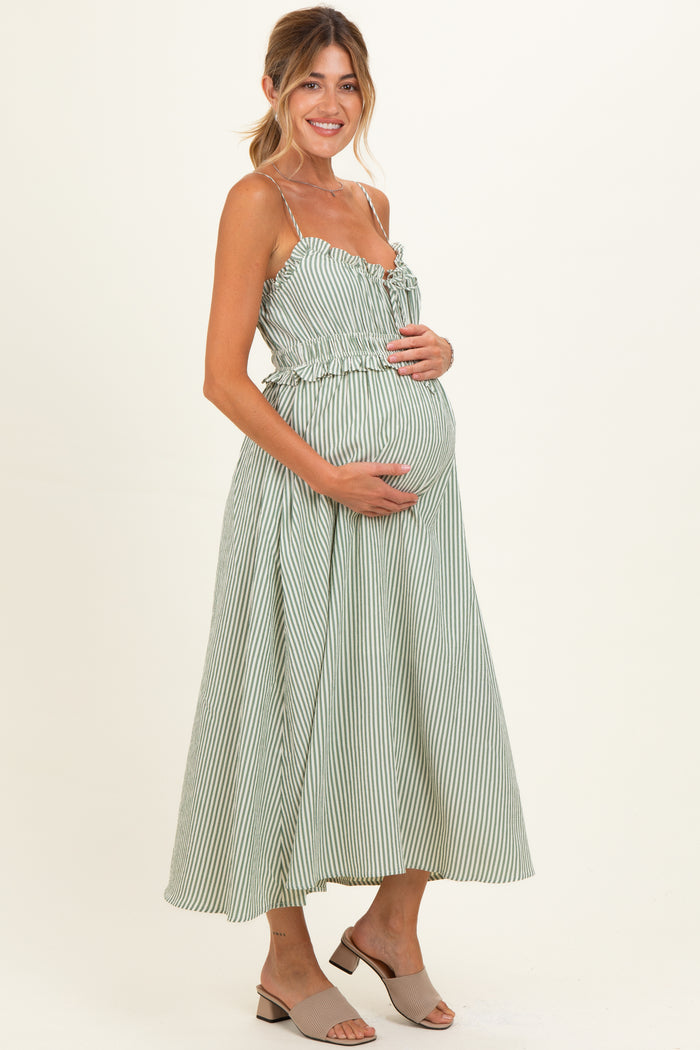woman wearing a green and white striped maternity dress with a gathered waist and holding her baby bump