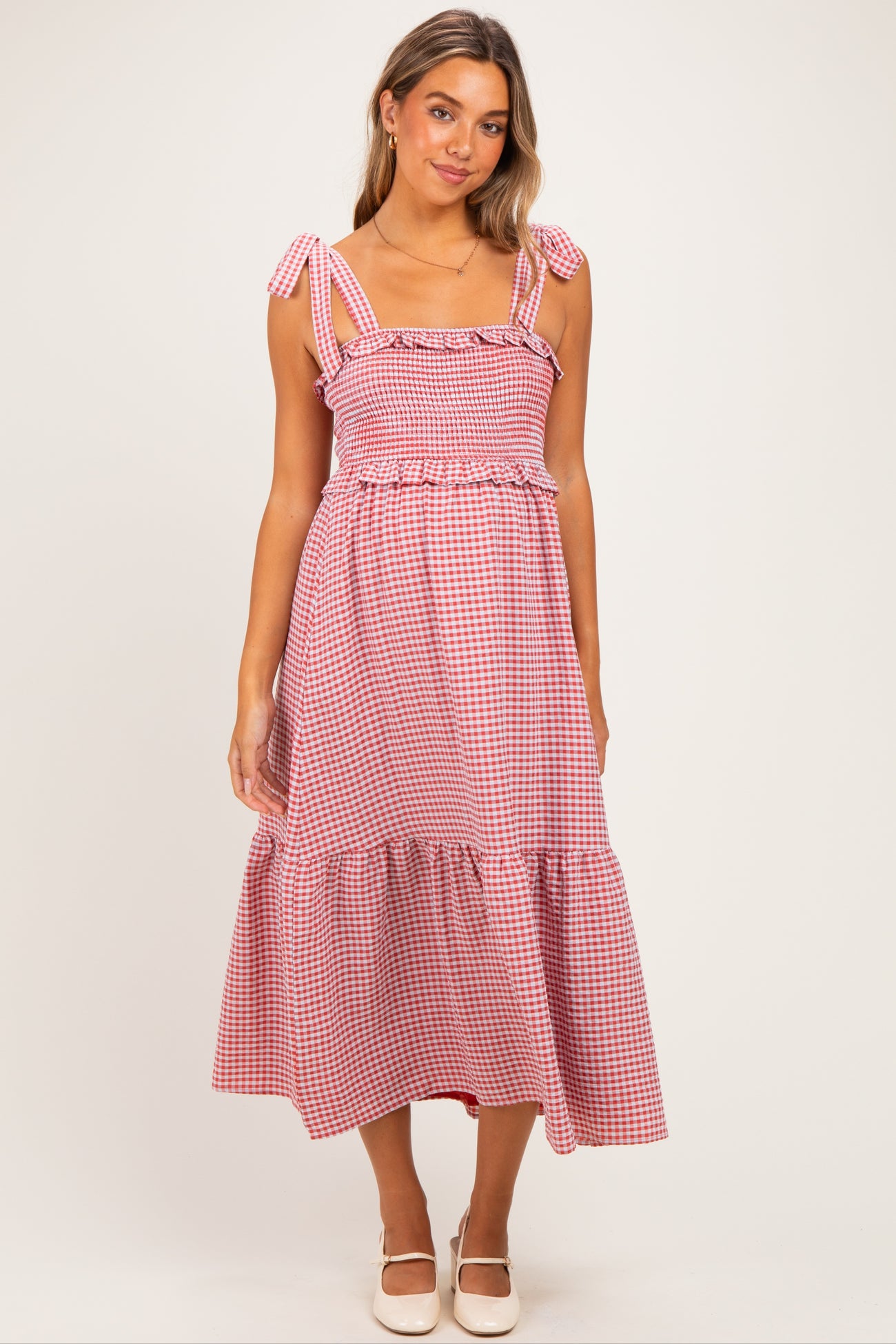woman wearing a red and white gingham maternity dress with ruffled straps and a tiered hem