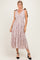 woman wearing a light pink sleeveless maxi dress with a tiered skirt and bow tie straps