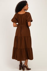 woman wearing a brown tiered maxi dress with short puff sleeves, showing the back view and gathered waistline