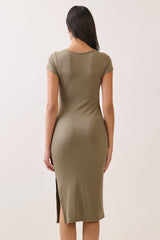 woman wearing a fitted olive green ribbed midi dress with short sleeves and a side slit, shown from the back