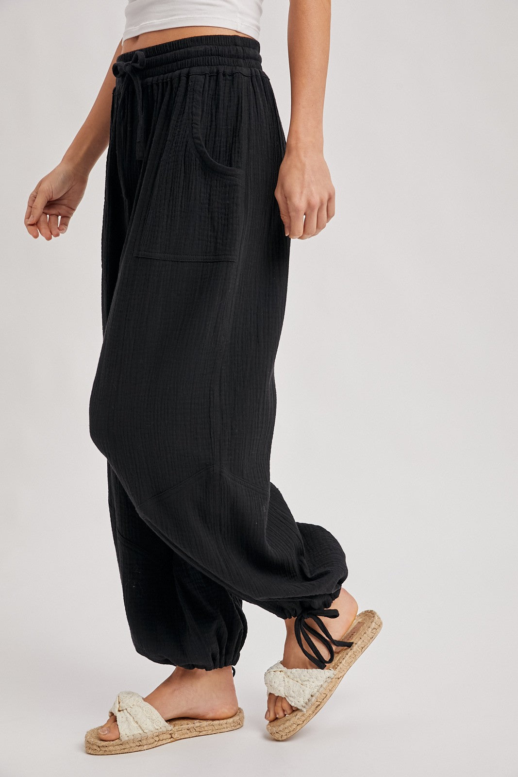 woman wearing black wide-leg lounge pants with a drawstring waist and side pockets, paired with fuzzy slippers