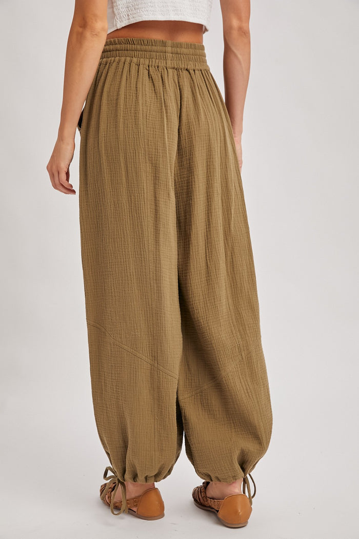 woman wearing olive green gaucho pants with an elastic waistband and drawstring detail at the ankle, viewed from the back