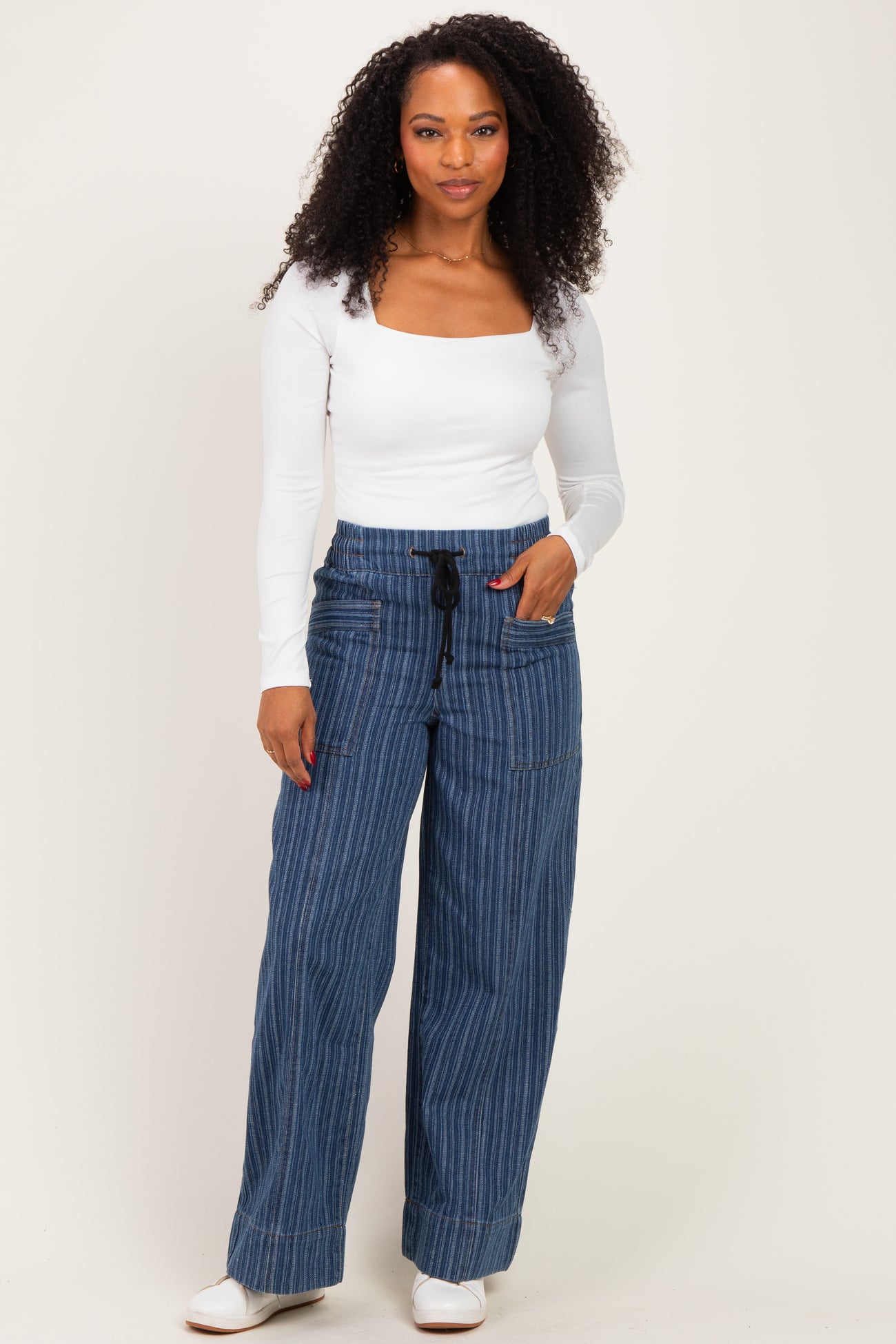 woman wearing a white long sleeve square neck top and blue pinstriped wide-leg pants with drawstring waist
