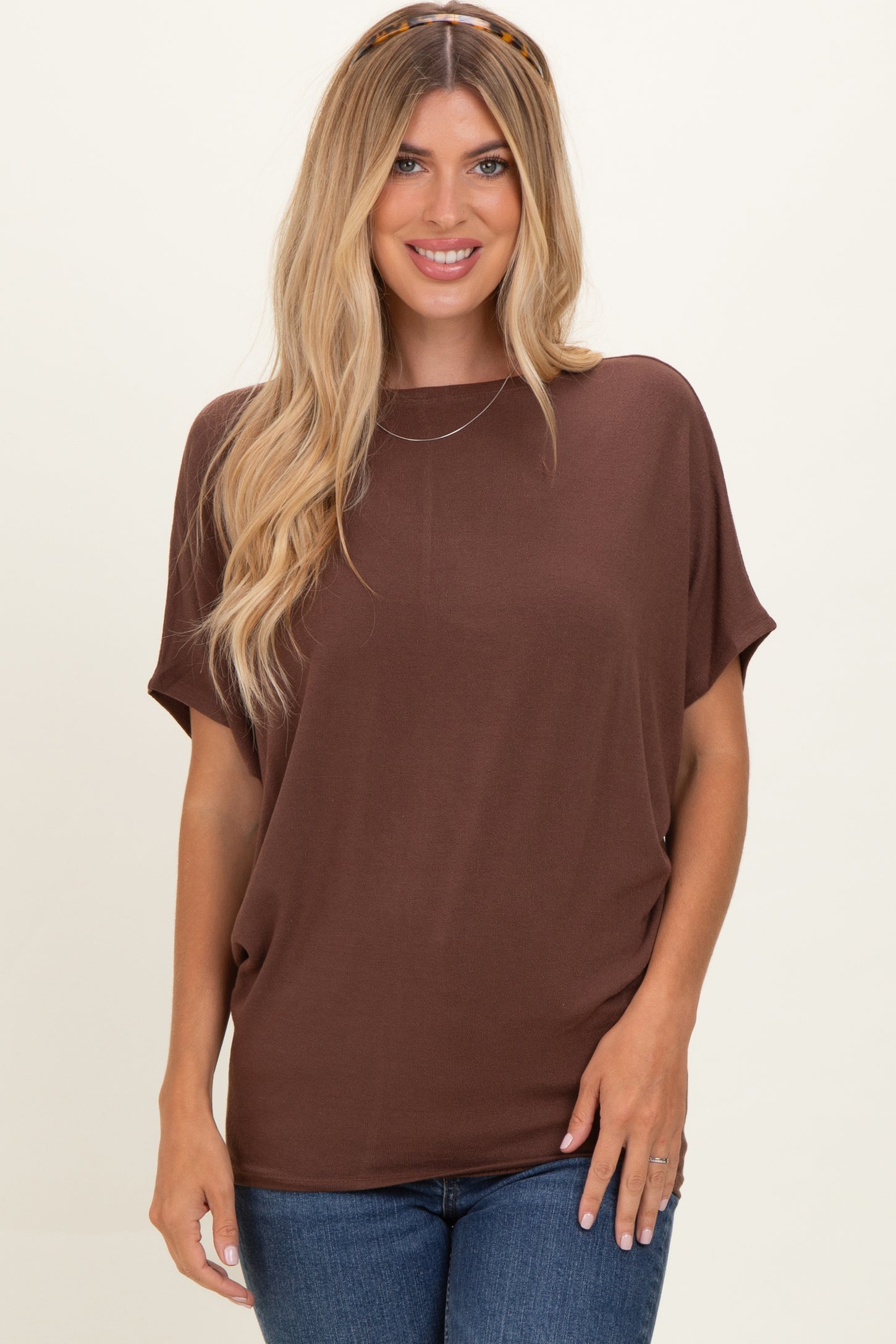 woman wearing a brown short sleeve top with a relaxed fit and denim jeans