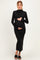 woman wearing a black long sleeve knitted maternity dress and holding her baby bump