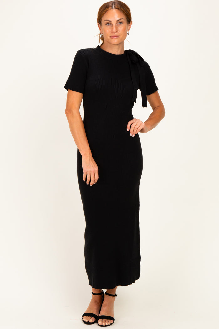 woman wearing a black ribbed knit maxi dress with short sleeves and a bow detail on the shoulder