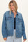 woman wearing a light wash denim jacket with front pockets and button closure, styled with a navy top and striped pants