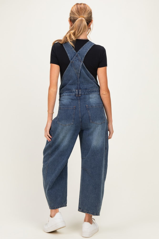 woman wearing a dark blue maternity denim overalls with a relaxed fit and pockets, styled with a black t-shirt underneath