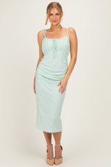 woman wearing a mint green lace midi dress with adjustable straps and a fitted silhouette