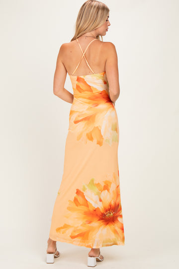 woman wearing an orange floral maxi dress with a back cross strap detail