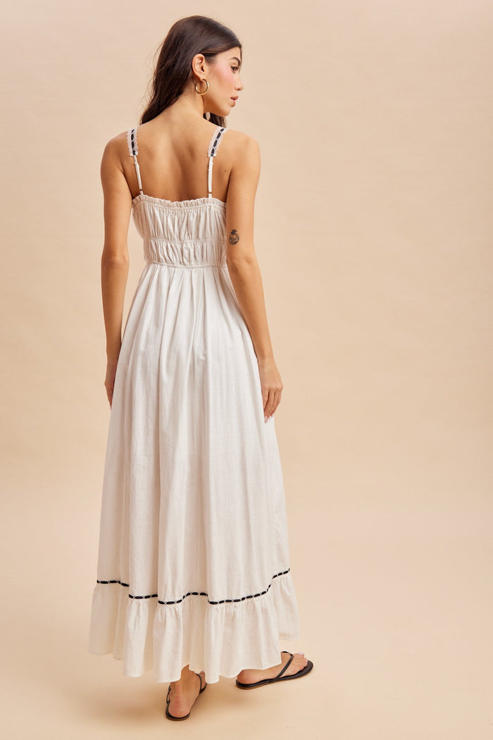 woman wearing a white maxi dress with smocked back and black detailing, viewed from the back