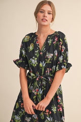 woman wearing a black floral midi dress with short puff sleeves and a tie waist detail