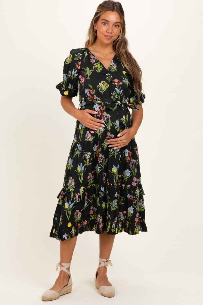 woman wearing a black floral maternity dress with ruffle details and a visible baby bump