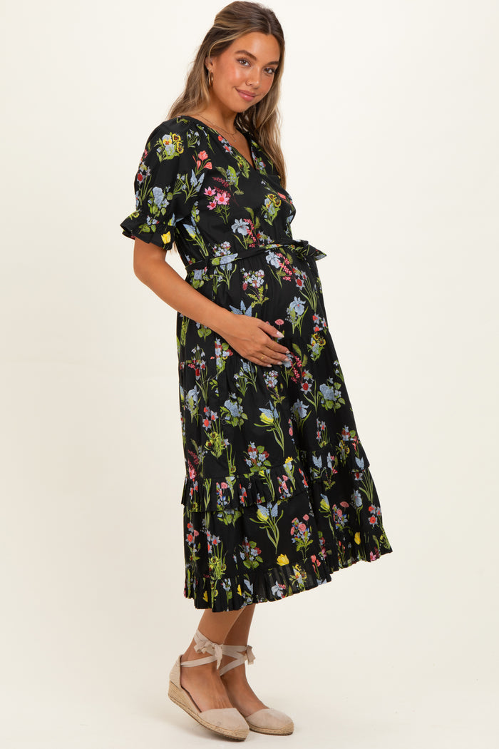 woman wearing a black floral maternity dress with ruffled hem and a visible baby bump