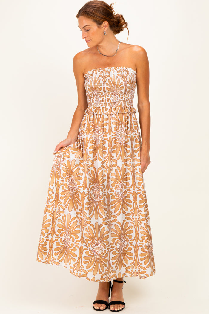 woman wearing a strapless bohemian floral maxi dress in beige and brown with a smocked bodice and flowy skirt