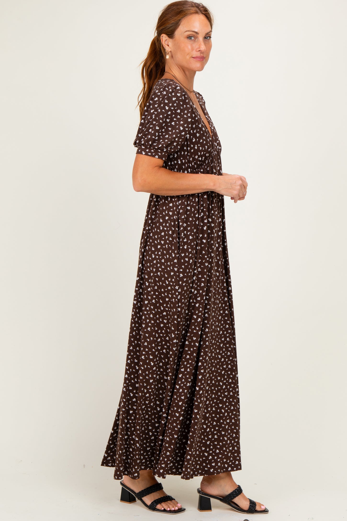 woman wearing a brown maxi dress with white polka dots and short sleeves, standing in profile