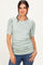 woman wearing a green floral short sleeve top with puff sleeves and ruched detailing, paired with denim jeans