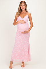 woman wearing a pink floral maternity maxi dress and holding her baby bump