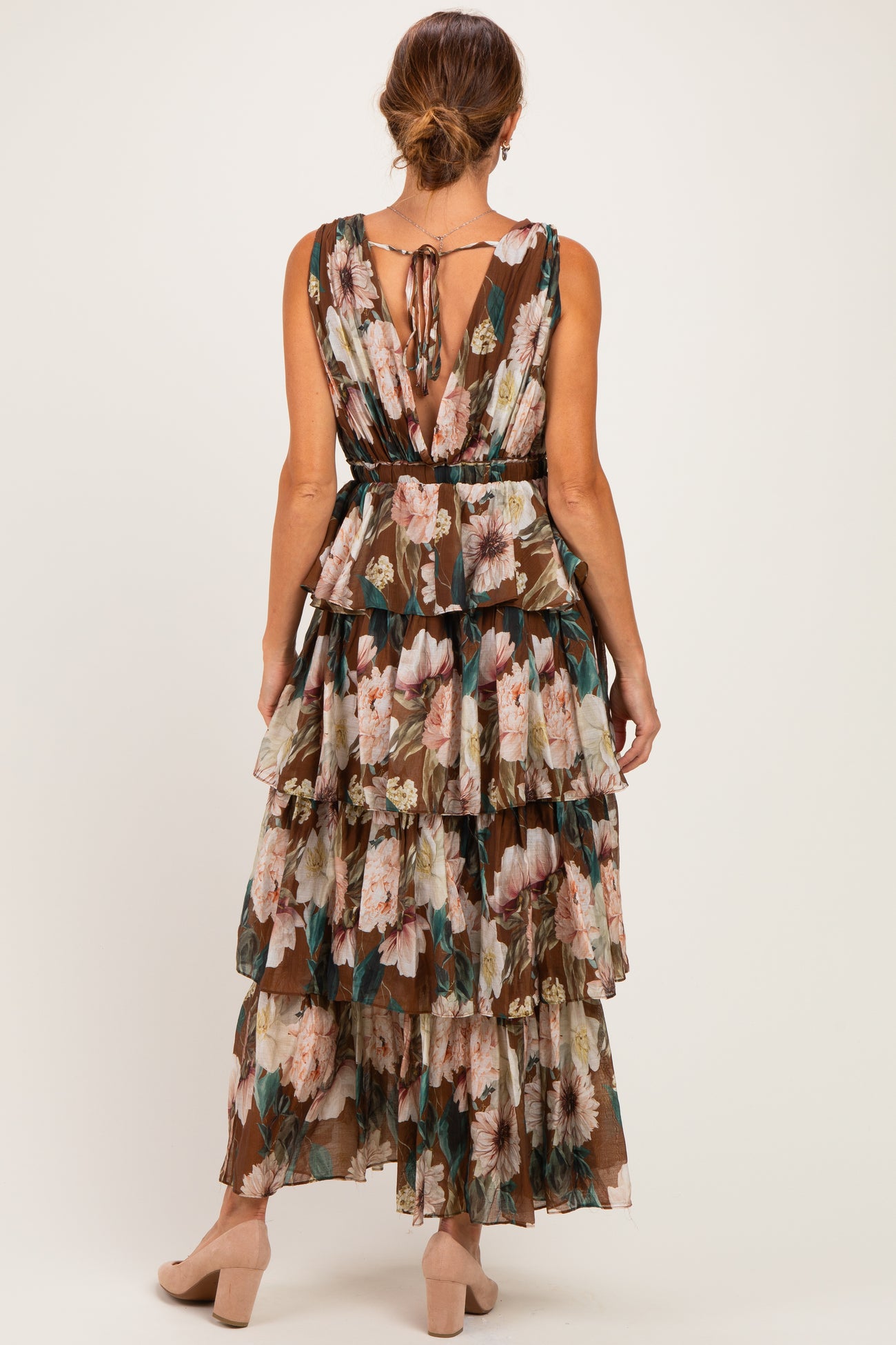 woman wearing a brown floral maxi dress with tiered ruffles and open back details
