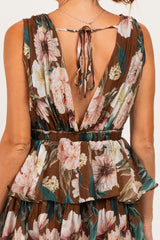 woman wearing a backless brown floral dress with ruffle details and a tie closure at the neck