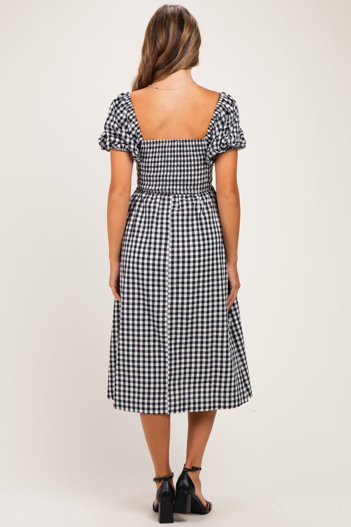 woman wearing a black and white gingham maternity dress with puff sleeves and a fitted bodice, showing a baby bump
