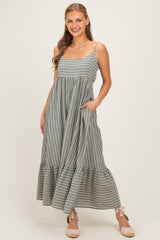 woman wearing a grey striped maxi dress with a ruffled hem and pockets, smiling at the camera