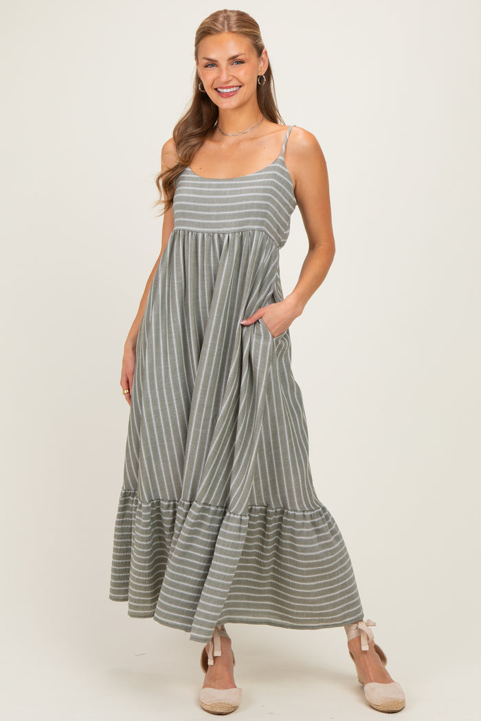 woman wearing a grey striped maxi dress with a ruffled hem and pockets, smiling at the camera