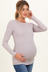 woman wearing a light mauve long sleeve ribbed maternity top and holding her baby bump
