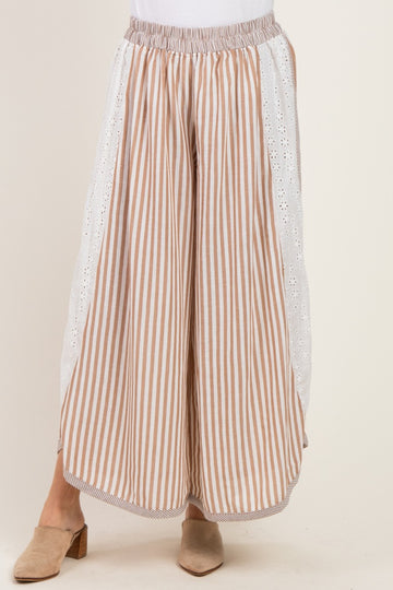 woman wearing beige and white striped wide-leg pants with eyelet lace detail on the sides